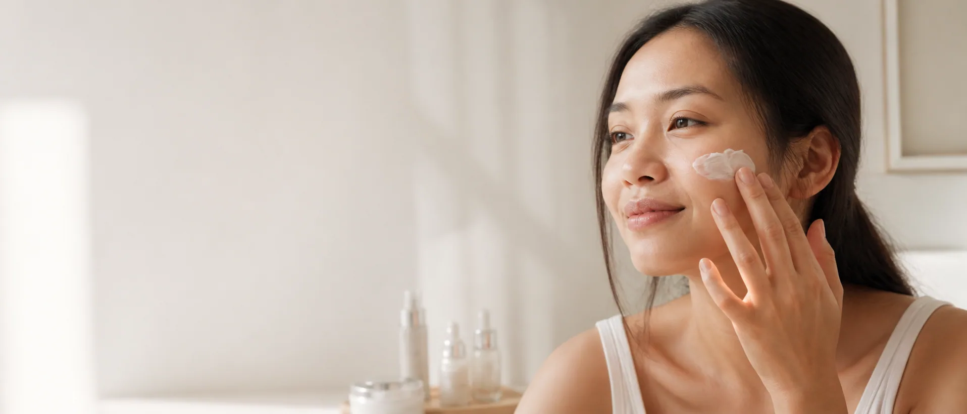 Woman applying facial moisturizer in a natural personal care routine